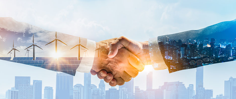 Images of wind turbines and city skylines superimposed behind two hands embraced in a business-style handshake.