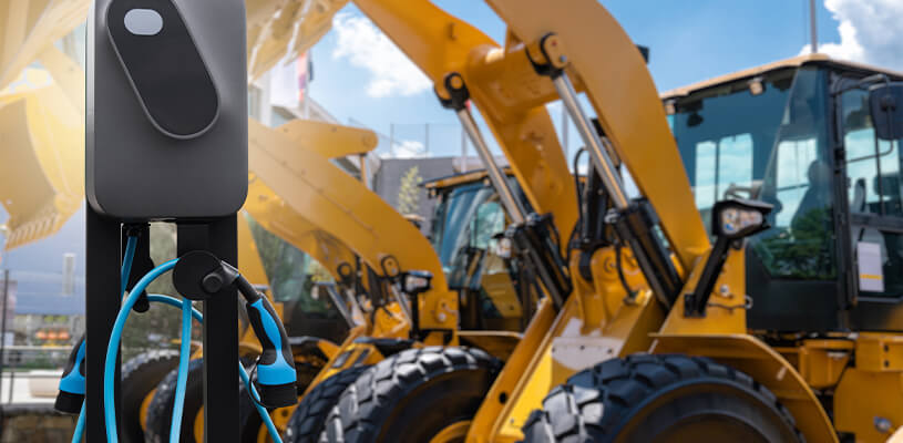 Electric heavy equipment parked near an ev charging station.